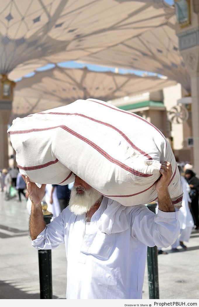 Man Carrying Load Under Masjid an-Nabawi Umbrellas - Al-Masjid an-Nabawi (The Prophets Mosque) in Madinah, Saudi Arabia -Picture