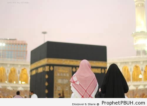 Muslim Man and Woman in Front of the Kaba at Maghrib Time - al-Masjid al-Haram in Makkah, Saudi Arabia